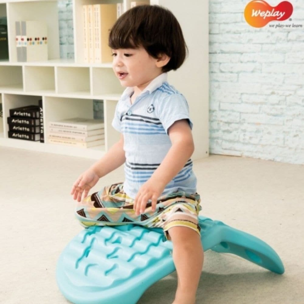Balance Rocking Whally Board, The WePlay® Whally Board is a fun balance board for kids! The Weplay Whally Board is inspired by a jumping fish, The Weplay Whally Board is textured with waves and bubbles on the surface to provide children with tactile stimulation's to feet and inspire the imagination of fish roaming freely in water. This ergonomic Whally balance board is designed for young children to either sit in or stand on for a fun rock balancing game. Special Play values: – Playing on the top side of We