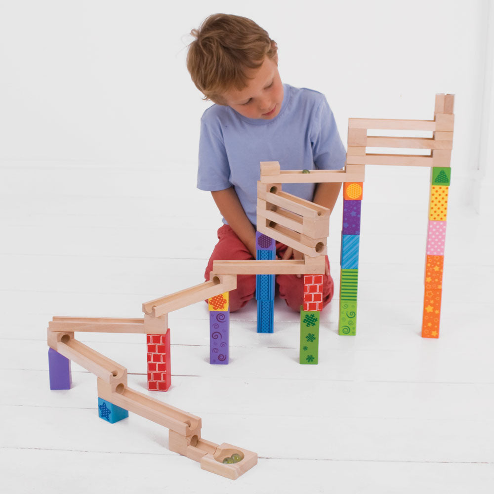 Bigjigs Toys Marble Run, Little builders can construct an impressive colourful Wooden Marble Run with this fun wooden toy! Place your marbles at the top and watch in delight as they roll down to the bottom! With 53 play pieces to choose from, there are endless possibilities for our marble run toy! The multicoloured printed blocks allow small hands to create funky designs. A fantastic way to encourage dexterity, hand-eye coordination and creativity. The Bigjigs Toys Marble Run is perfect for creative play se