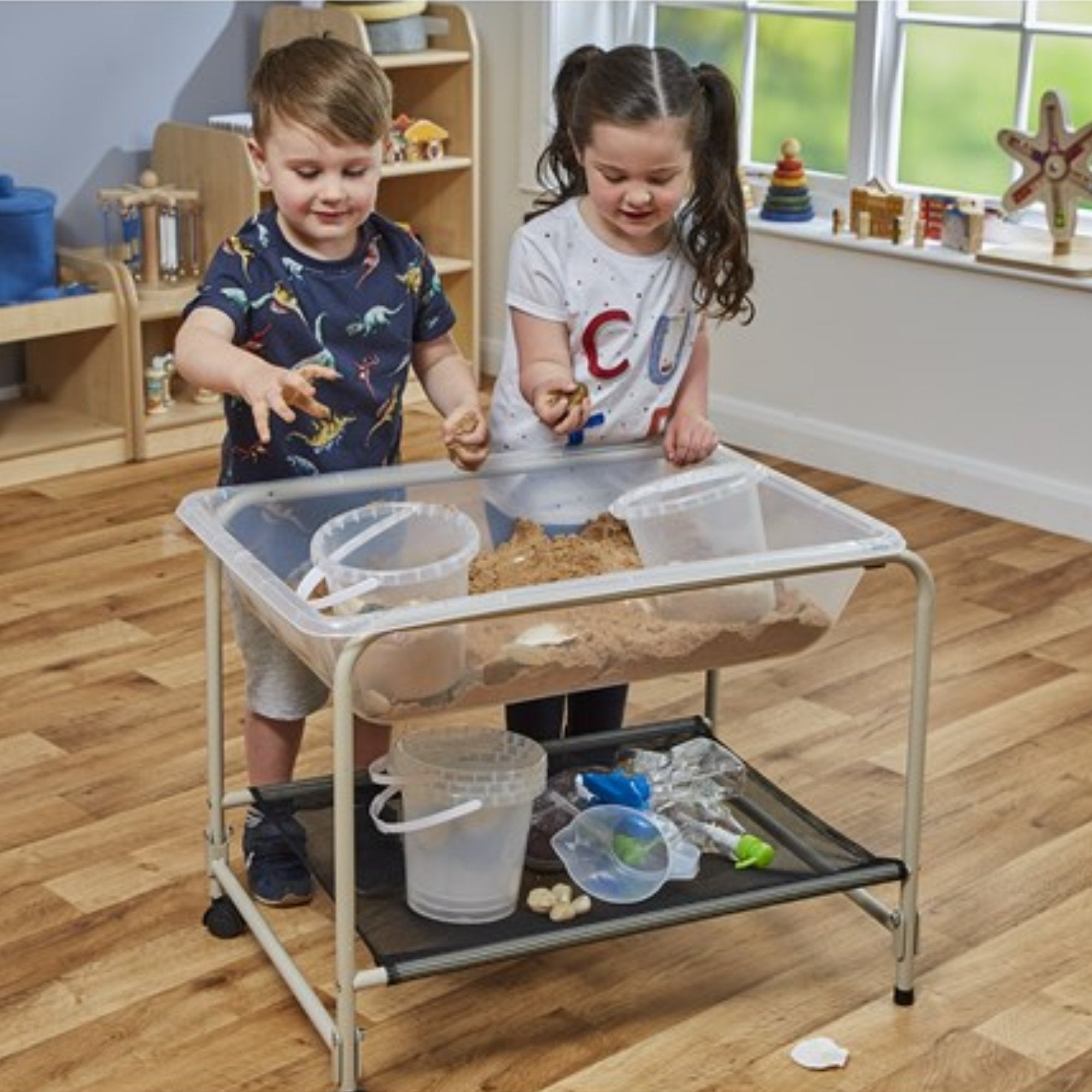 Clear Desktop Sand and Water Tray with Stand, Introducing the Clear Desktop Sand & Water Tray with Folding Sturdy Steel Stand, the perfect addition to any classroom or play area. This versatile tray is designed for endless hours of sensory play and exploration.Crafted from sturdy plastic material, the clear tray provides a captivating view of the contents inside, while ensuring durability and resistance to wear and tear. The steel stand with powder-coated frames adds a touch of robustness to the table, ensu