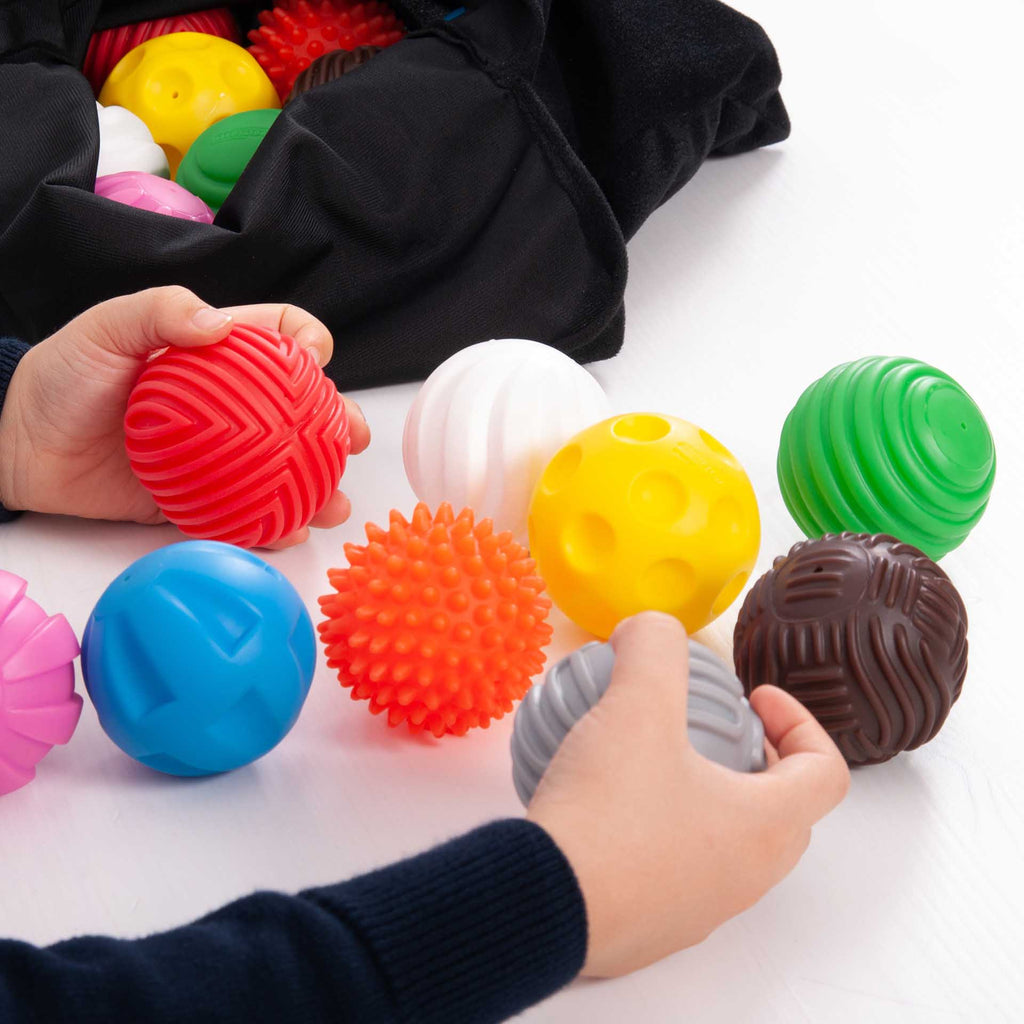 Discovery Ball Activity Set Pack 18, The Discovery Ball Activity Set is a versatile sensory ball set that contains 9 pairs of differently tactile colourful balls in a black feely bag. The Discovery Ball Activity Set will encourage sensory exploration, is ideal for child-led learning activities and can be used in a variety of ways: learning colour names; counting in twos; describing textures visually or by touch; sorting and matching the pairs by colour; counting and sorting the different patterns; simple ma