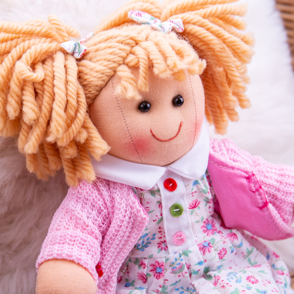 Poppy Doll - Small, Poppy Doll is ready to meet her new little best friend! Poppy is a soft and cuddly ragdoll dressed in an adorably cute outfit. This soft and cuddly doll is a fashion trendsetter with her bright dress and cute pink cardigan. She's kind and loving and likes nothing more than to share a secret and a hug. Poppy Doll’s soft material makes her the perfect toddler doll as she’s small (only 28cm tall) and gentle on little hands. Poppy the ragdoll can easily fit into bags, prams, cots, beds and c