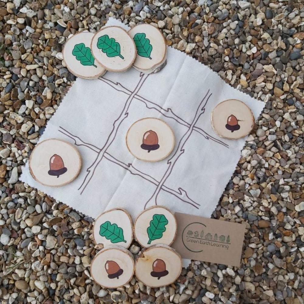 Acorns & Oak Leaves Tic Tac Toe, Elevate the beloved game of Tic Tac Toe with a delightful natural twist! Our Acorns & Oak Leaves Tic Tac Toe set is more than just a game; it's a charming, educational experience that merges tradition with nature. Key Features: Nature-Inspired Design: Features 10 hand-painted birchwood discs—5 shaped like acorns and 5 like oak leaves. Handy Storage: Comes complete with a calico game grid and a cotton drawstring travel bag for easy storage and portability. Quality Craftsmansh