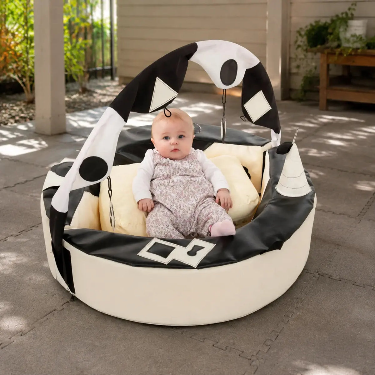 Crescent Ring with Activity Arch in a covered play area with baby