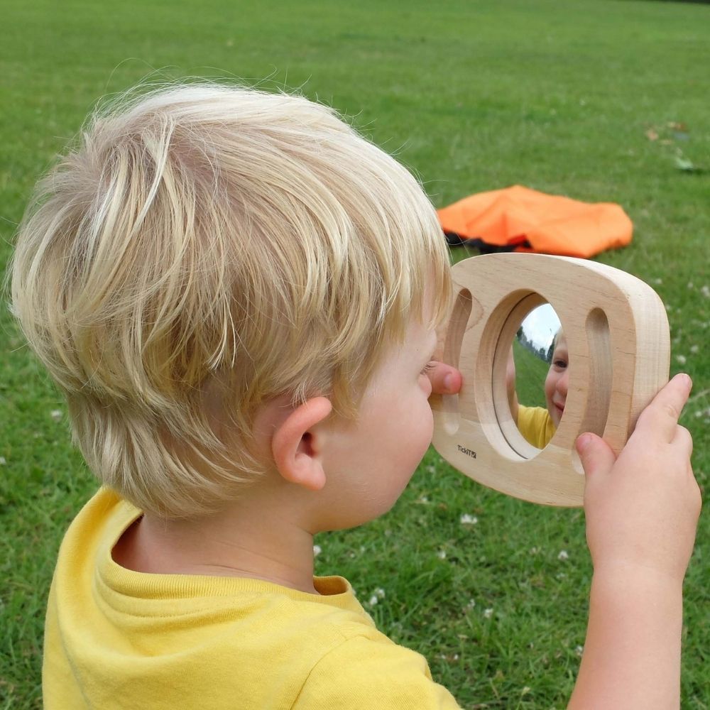 Easy Hold Convex Concave Mirror, The TickiT Easy Hold Convex/Concave Mirror is a delightful and easy to hold concave mirror. The TickiT Easy Hold Convex/Concave Mirror is a fantastically safe hand held acrylic mirror which children love to use to explore there own facial expressions and features. The TickiT Easy Hold Convex/Concave Mirror has a rubberwood frame with easy grip handles enclosing a concave and convex mirror. The TickiT Easy Hold Convex/Concave Mirror produces fascinating reflections – upside d