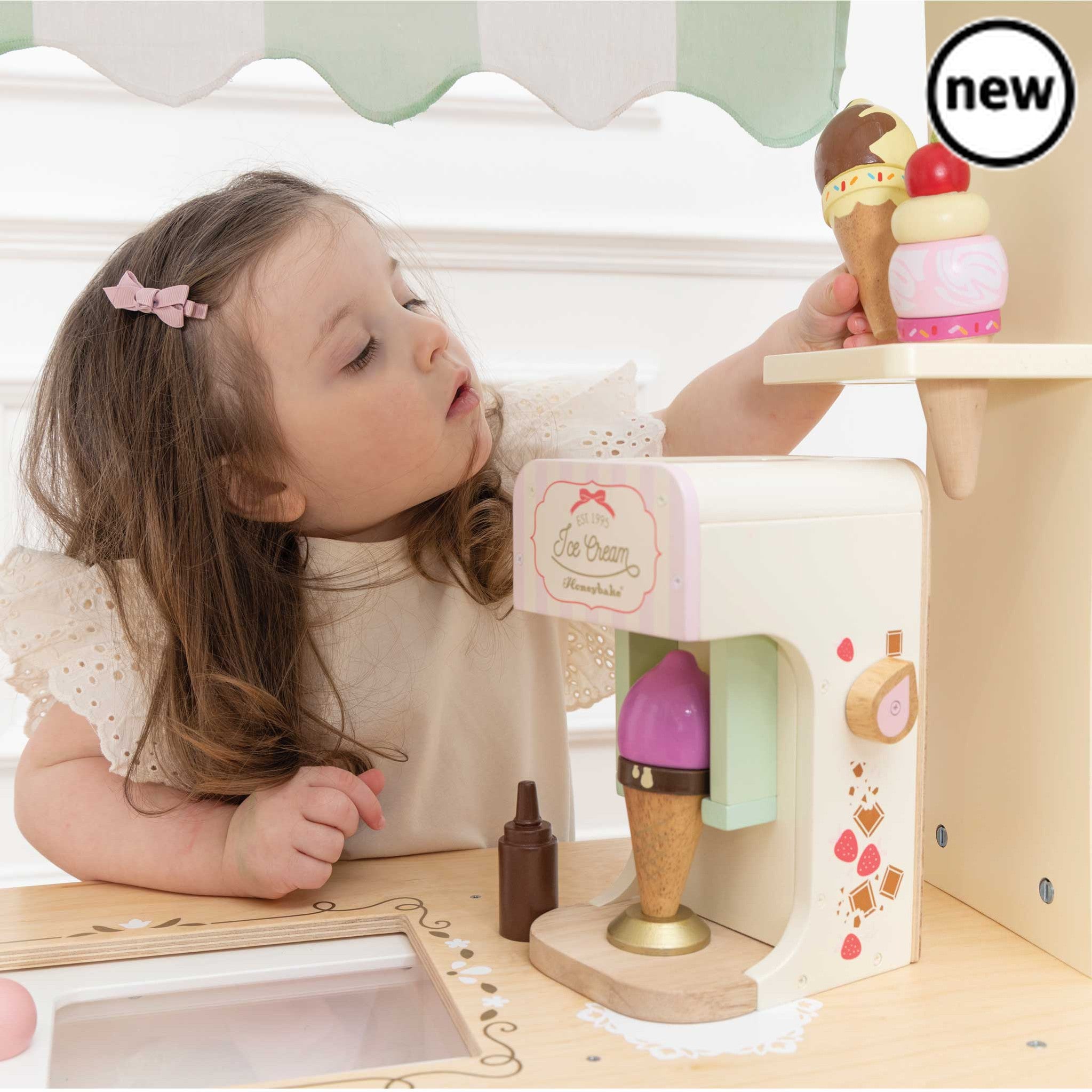 Ice Cream Trolley and Treats, This whimsical Ice-Cream Trolley toy is a nostalgic nod to bygone days and fairs, encouraging both imaginative play and a sense of wonder in children. Key Features Design: The trolley features a barrow style with a classic striped fabric canopy that adds to its vintage allure. Material: Crafted from sustainable wood, this toy is built to last for a lifetime of inspired play. Realistic Features: With an ice compartment featuring a sliding door, the trolley reveals illustrations 