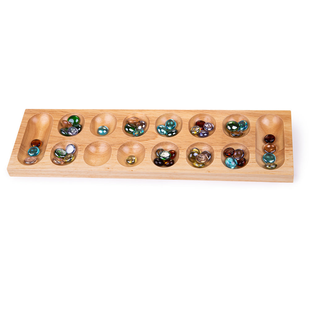 Mancala, Mancala is a two-player board game where the aim of the game is to collect more marbles than your opponent. This fun yet simple wooden board game comes with two rows of six holes and a long mancala at either end. Wondering how to play mancala? Begin by placing the four stones into each hole (don’t include the mandalas). To decide who’s going first by flipping a coin or doing rock-paper-scissors. During their turn, players must collect all of the marbles in a hole on their side of the board and drop