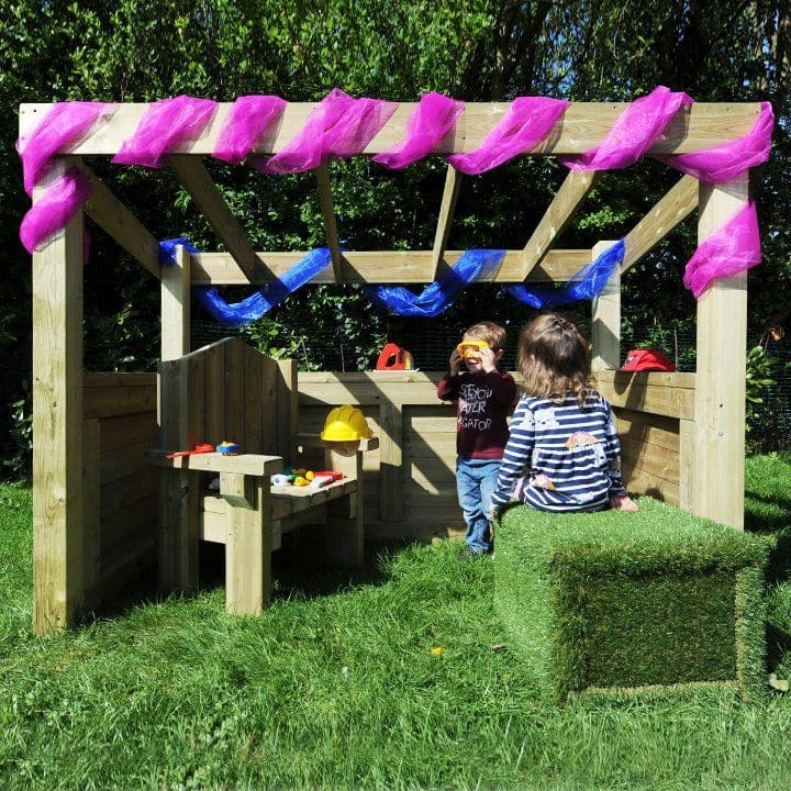 Outdoor Wooden Role Play Centre, This beautifully finished, open ended wooden structure will make a fantastic addition to your outdoor role play area. What will it be today – a home corner, shop, busy garage or simply a cosy den? The open design will lend itself to many different possibilities.The roof is slatted so mobiles and weaving shapes can be hung from it, or peg some fabric on top to make a cosy space. Beautifully finished for a quality appearance. The wood has a 10 year guarantee against rot and in