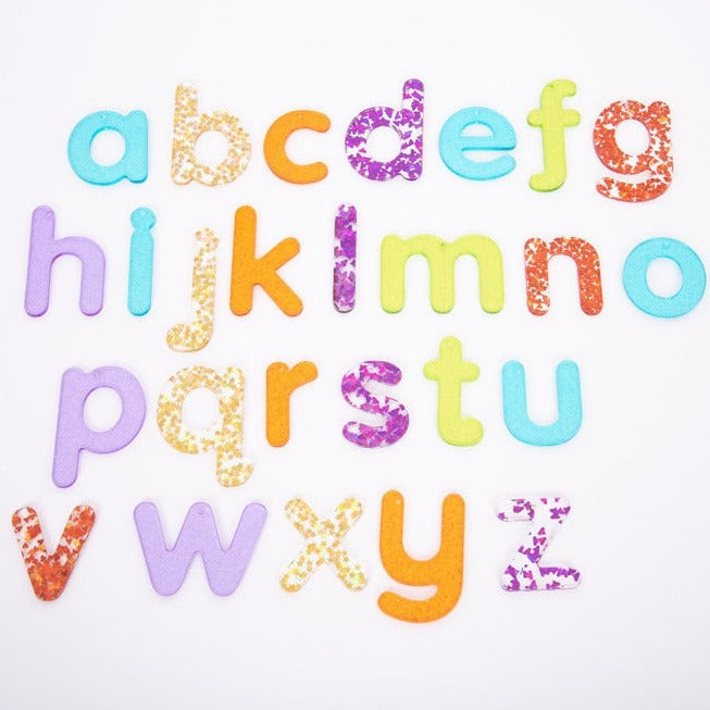 Rainbow Glitter Letters - Pk26, The Rainbow Glitter Letters come as a set of 26 sparkling glitter lower case letters a-z in a child friendly font made from colourful translucent 3mm acrylic. The Rainbow Glitter Letters come in 7 colours, with the vowels in turquoise. Ideal for use on a light panel to make letter recognition interesting and exciting. Rainbow Glitter Letters come with a 2.5mm hole at the top balance point so they can be strung up against a window or outdoors to create fascinating colour glitt