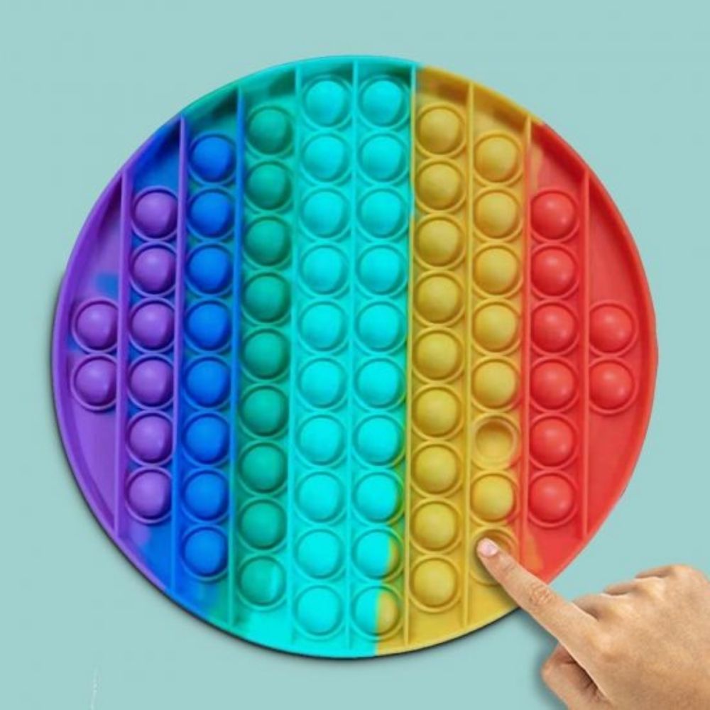 Rainbow Push Popper Jumbo Mat, Extra large version of our best-selling Rainbow Push Popper. This rainbow coloured pad is covered in bubbles that make a satisfying pop sound when pushed inwards, similar to bubble wrap. After one press, the bubble then appears on the other side, ready to be pushed and popped all over again. This fiddle toy is immensely satisfying to use, and is proving to be a big hit with popular Tik Tok users and other social media influencers. Large plastic pad with popping bubbles Trendin