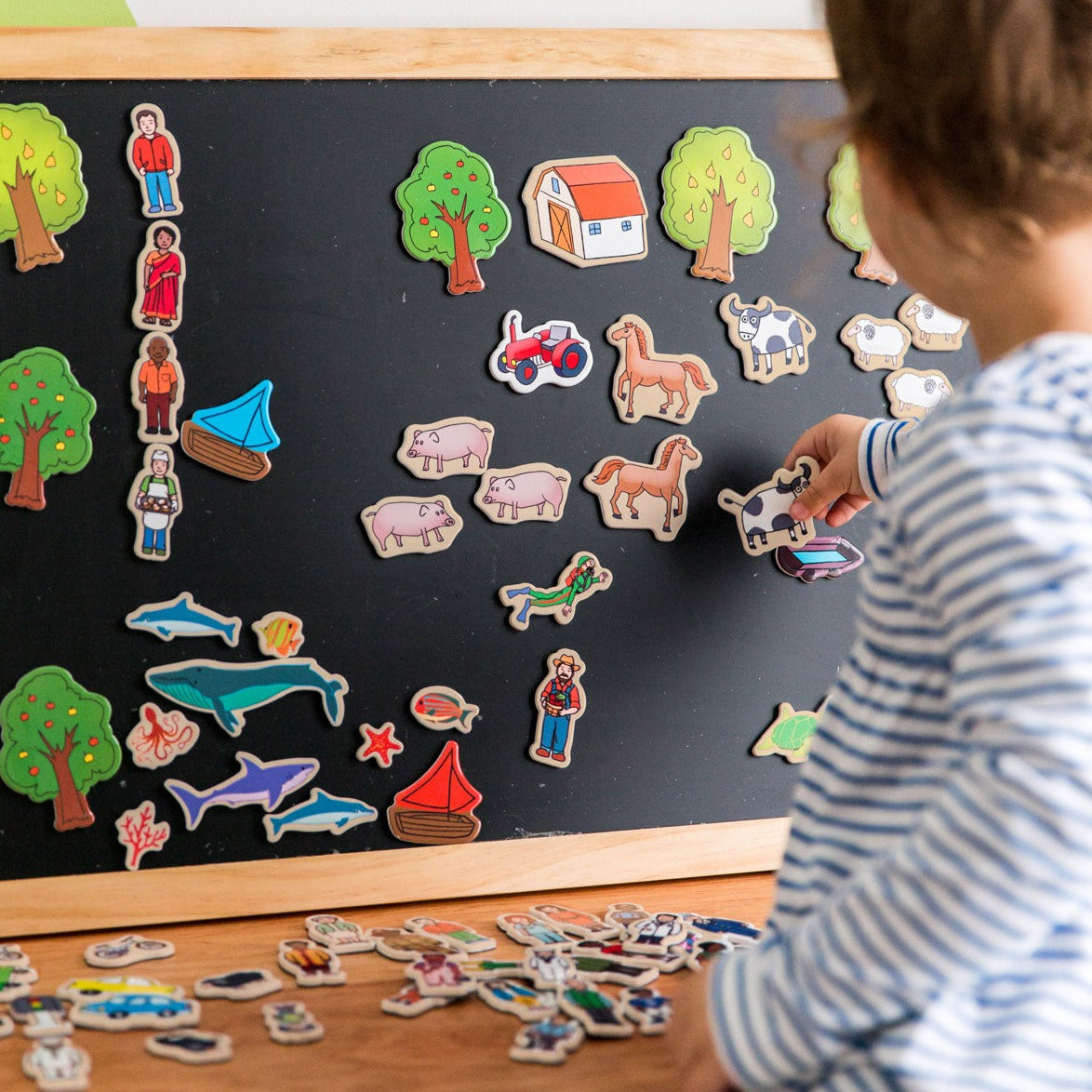 Tell a Story Magnetic Board, Introduce your child to the joys of creative play and storytelling with our ultimate storytelling board! This amazing set provides the perfect opportunity for your child to explore their imagination while also opening up conversations about different roles within our community.Featuring a generously sized hanging magnetic chalkboard as the background, this set includes 75 thick wooden magnetic pieces that feature a diverse range of people from different ages, genders, ethnic bac
