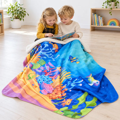 Two children sharing a book with one Sea Life fleece throw over their laps