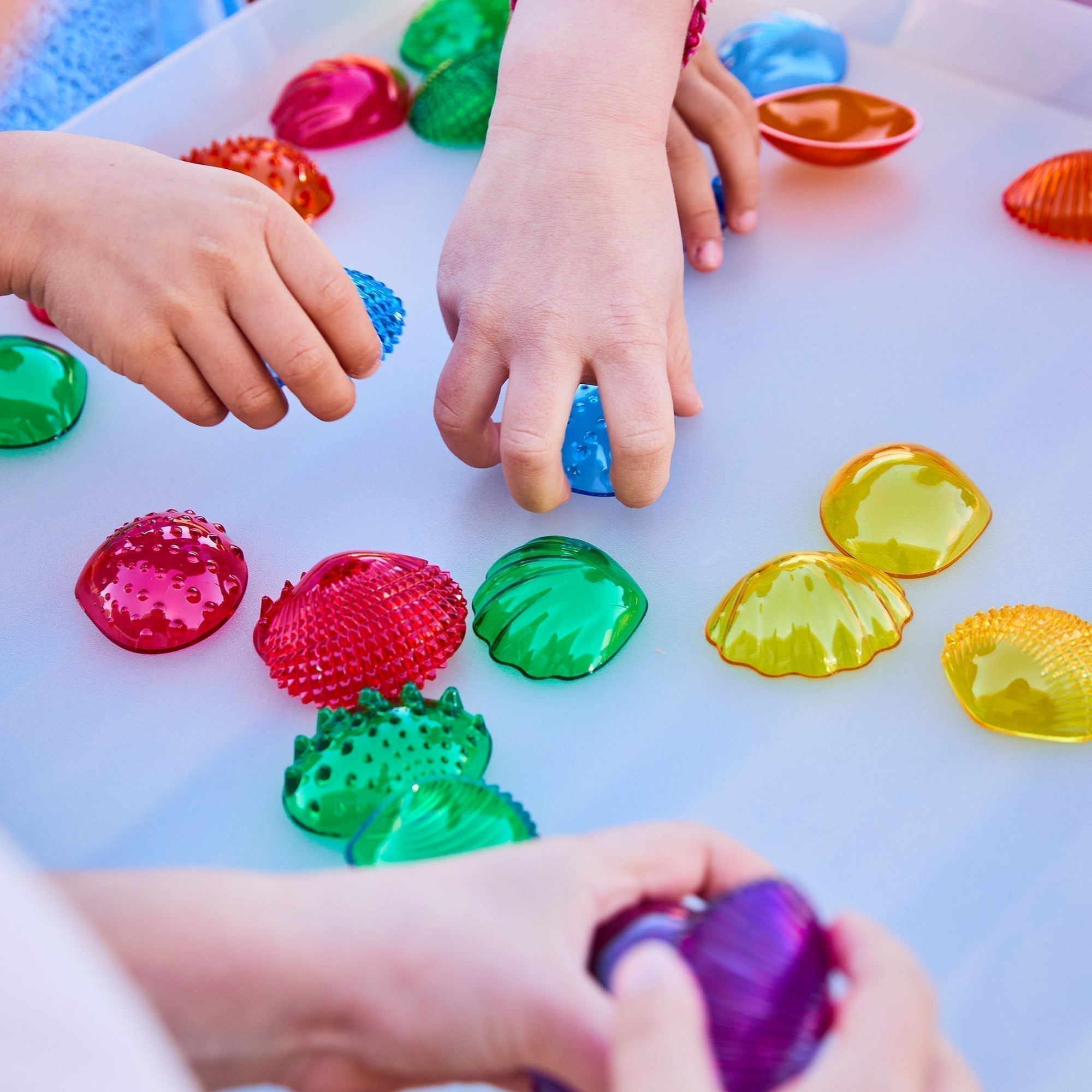 Transparent Tactile Shells - Pk108, The Transparent Tactile Shell's are beautiful translucent colour seashells in 2 sizes and 6 colours with 6 different tactile surfaces. Children will love to touch and feel these Transparent Tactile Shells, describing the differences and similarities as well as discovering the colours and colour-mixing opportunities they provide. The Transparent Tactile Shells - Pk108 are ideal to teach early number concepts such as sorting, matching, comparing, sequencing, patterning and 